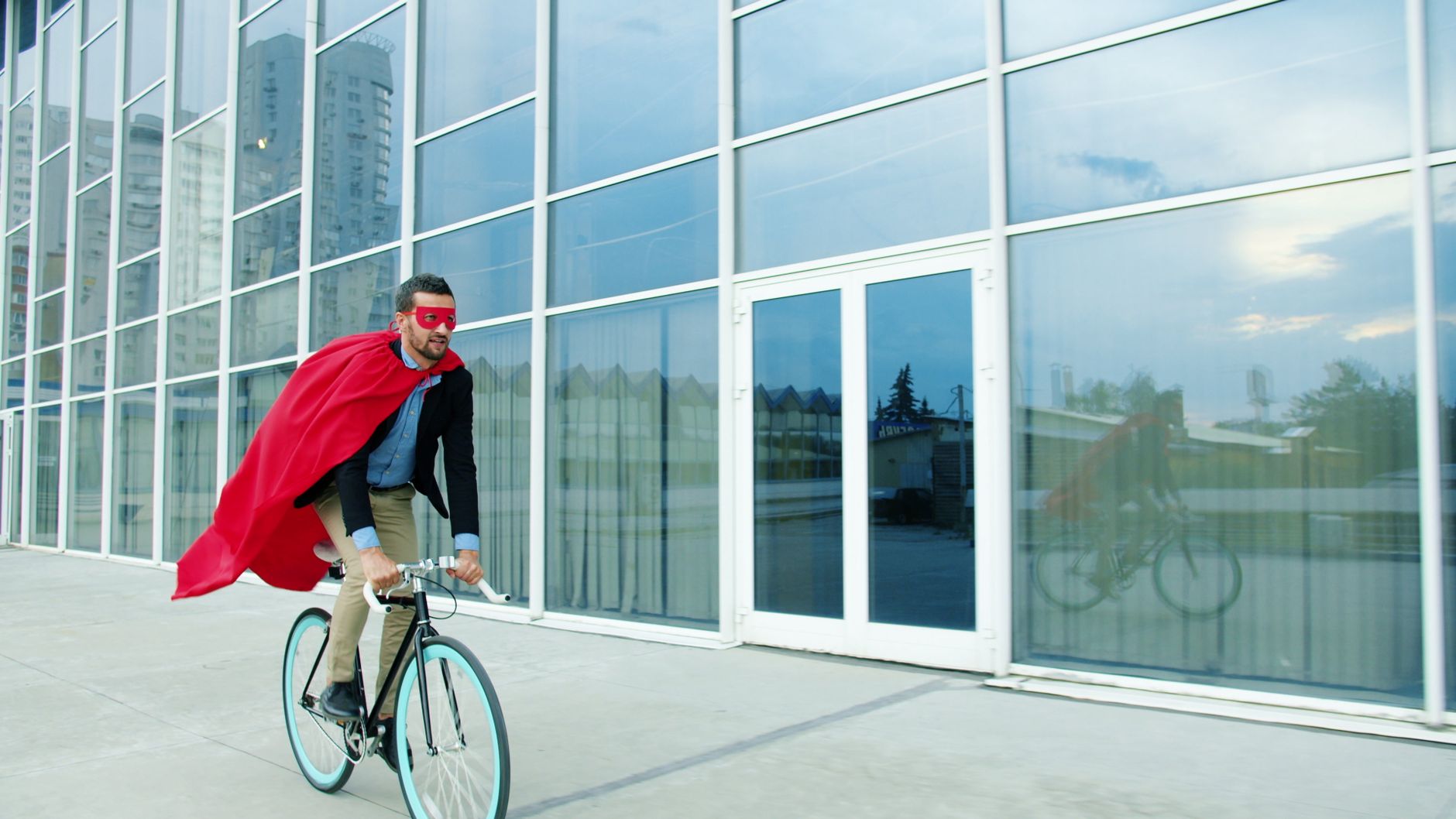 man in superhero costume riding bicycle outdoors